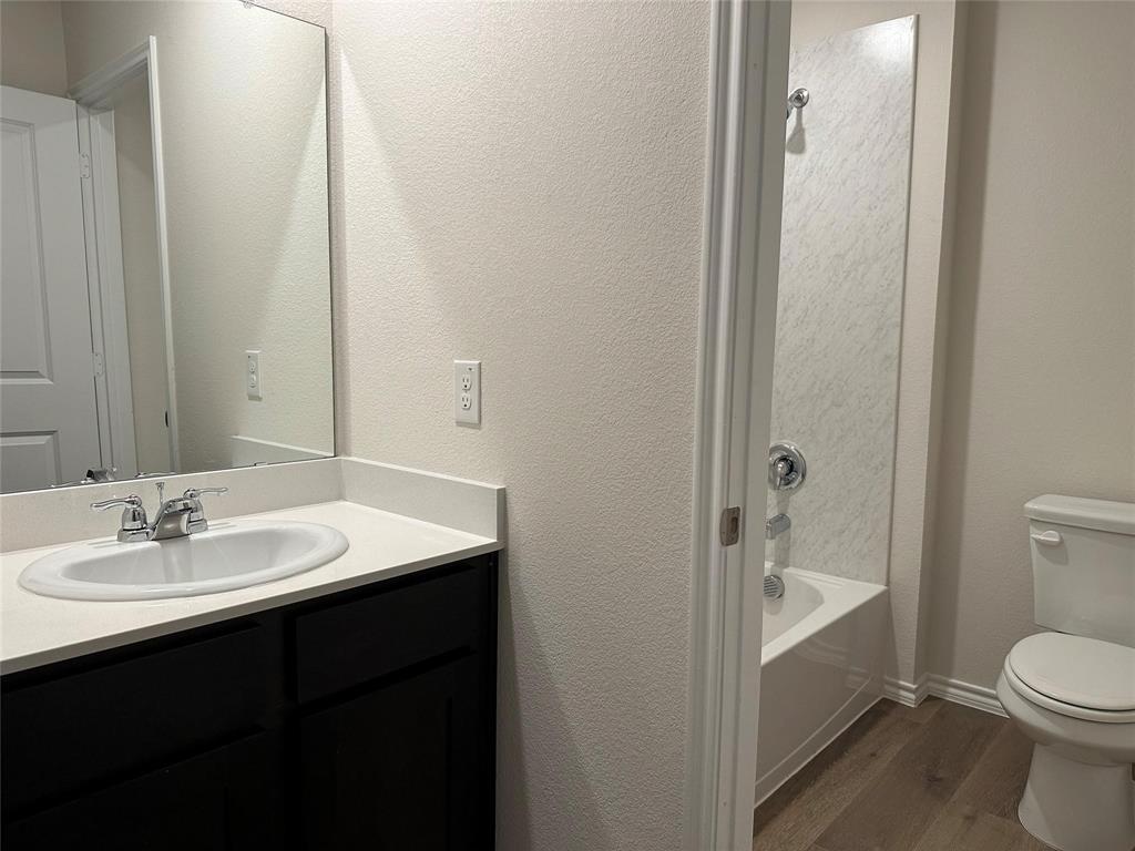 Bathroom with dark wood-style flooring, vanity, and shower / washtub combination