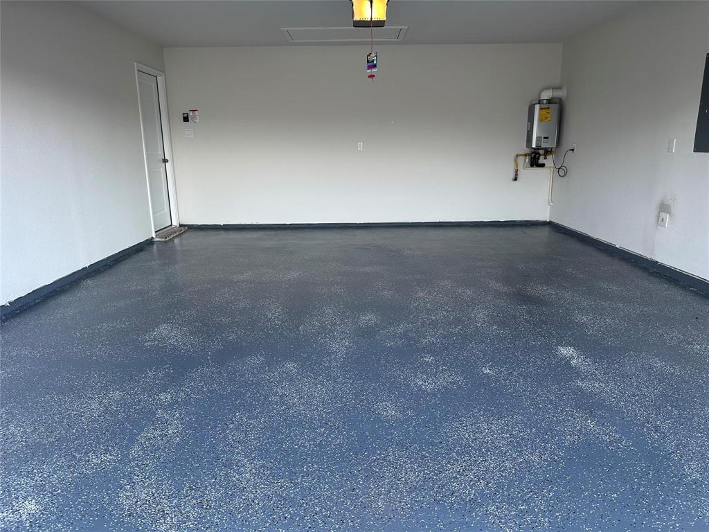 Garage with a garage door opener, tankless water heater, and electric panel