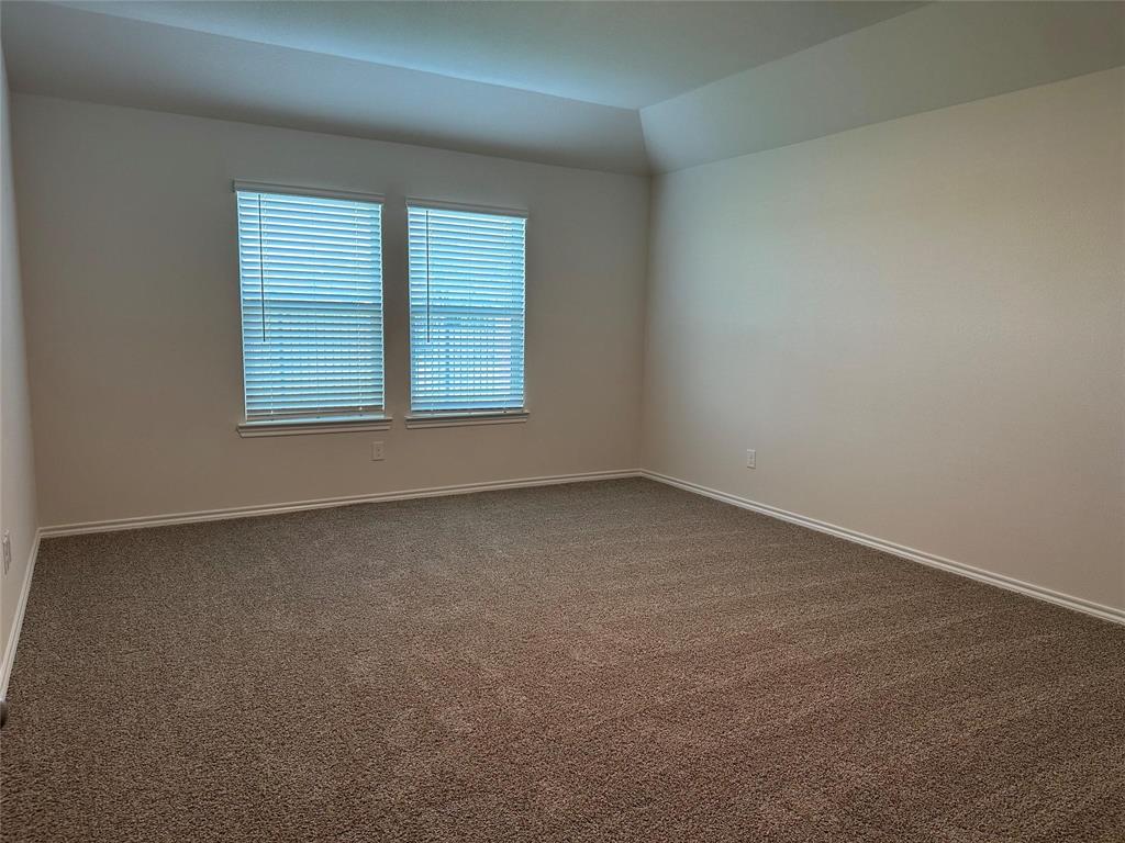 Unfurnished room featuring carpet flooring and lofted ceiling