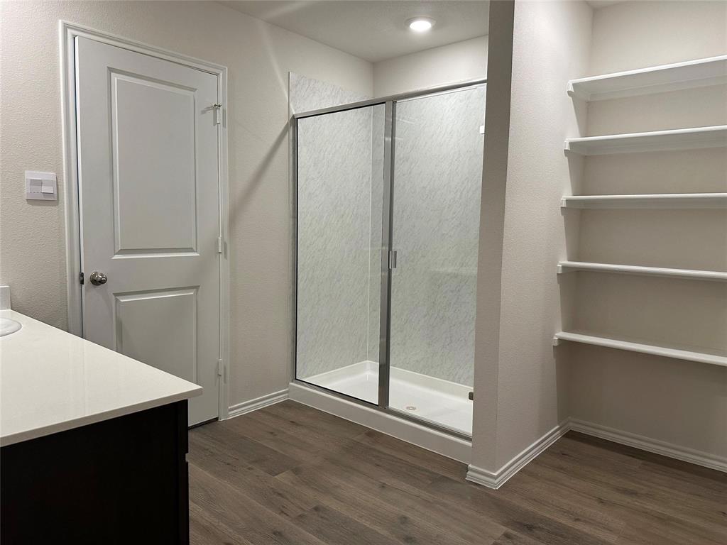 Full bath with a shower stall, vanity, dark wood finished floors, and a closet