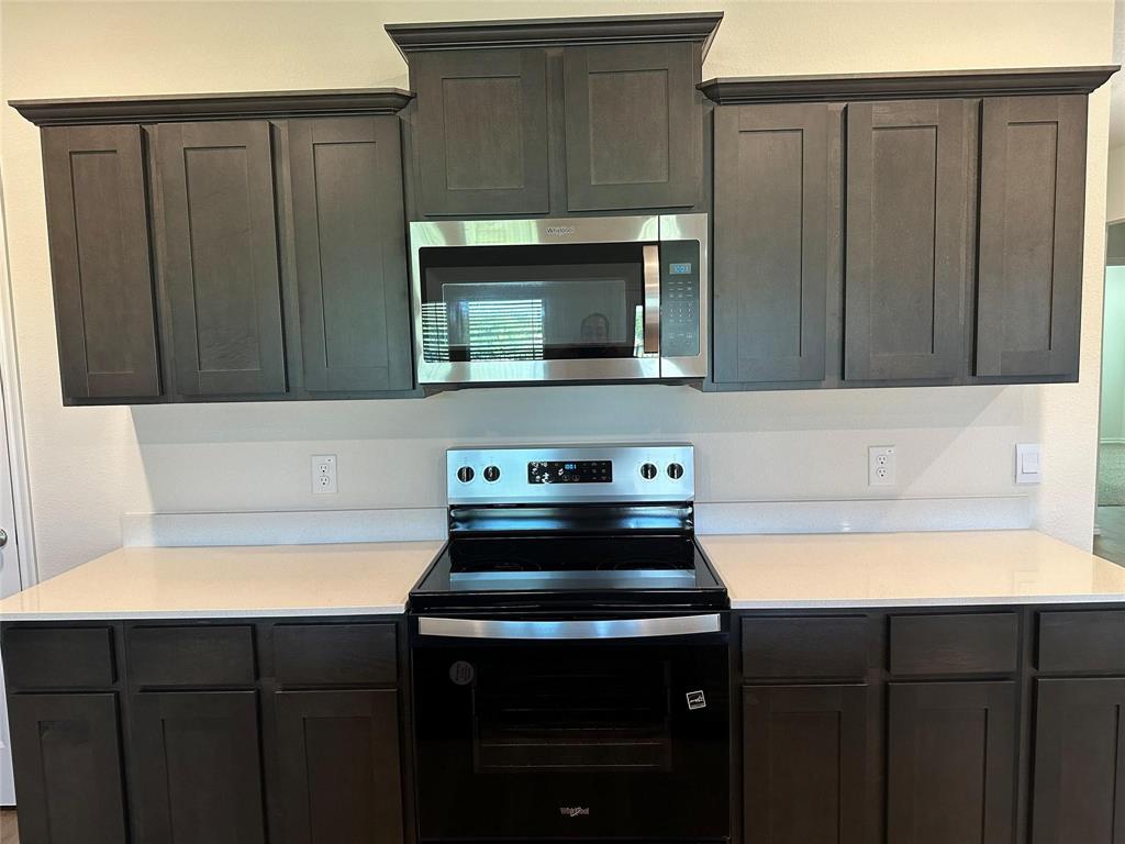 Kitchen with electric range oven, stainless steel microwave, and dark brown cabinets