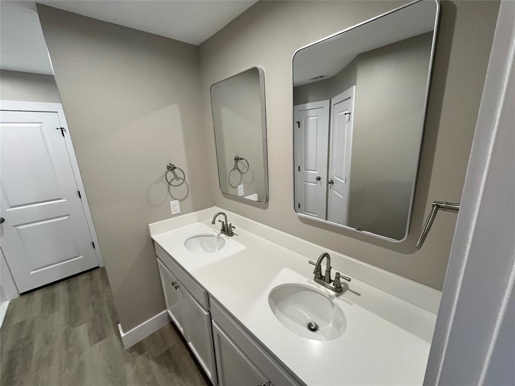 Double vanity featuring a light-toned countertop, dual inset sinks with brushed metal faucets, soft-close cabinetry, and two rectangular wall-mounted mirrors