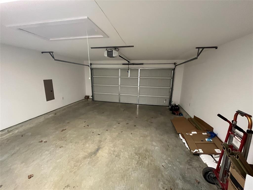 Attached two-car garage featuring a sectional metal garage door, ceiling-mounted automatic door opener, and concrete flooring