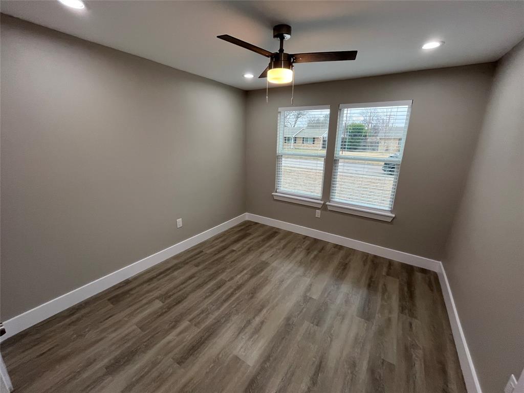 Neutral-toned room featuring wood-finish flooring, recessed lighting, double-pane windows with horizontal blinds, and a central ceiling fan with an integrated light fixture