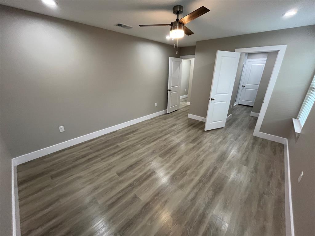 Room featuring wood-finish flooring, neutral wall paint, recessed lighting, a ceiling fan with integrated light, and paneled interior doors