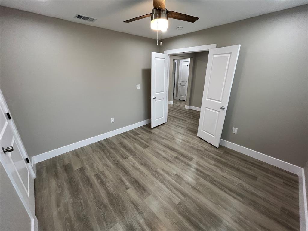 Room featuring wood-finish flooring, two-panel interior doors, and a ceiling-mounted light fixture with a fan