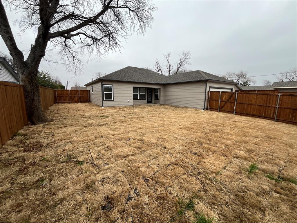 Rear exterior featuring horizontal lap siding, a hip roof with asphalt shingles, and a fully enclosed wood privacy fence