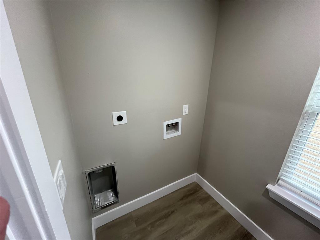 Dedicated utility space featuring wood-finish flooring, a recessed dryer vent, plumbing hookups, and a window with blinds Dedicated utility space featuring wood-finish flooring, a recessed dryer vent, plumbing hookups, and a window with blinds
