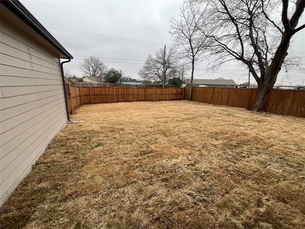 Rear yard featuring horizontal siding, a wood privacy fence, and mature trees
