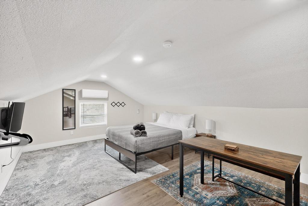 Vaulted ceilings featuring recessed lighting, wall-mounted climate control unit, and wood-finish flooring