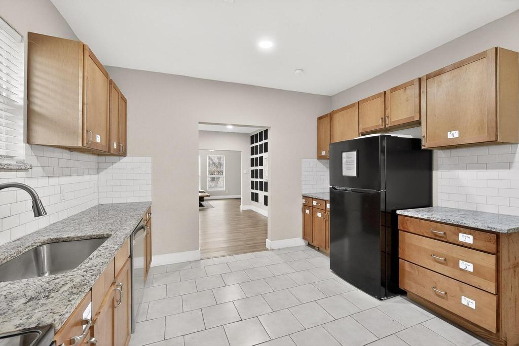 Kitchen featuring light wood cabinetry, stone-surface countertops, white subway tile backsplash, and ceramic tile flooring