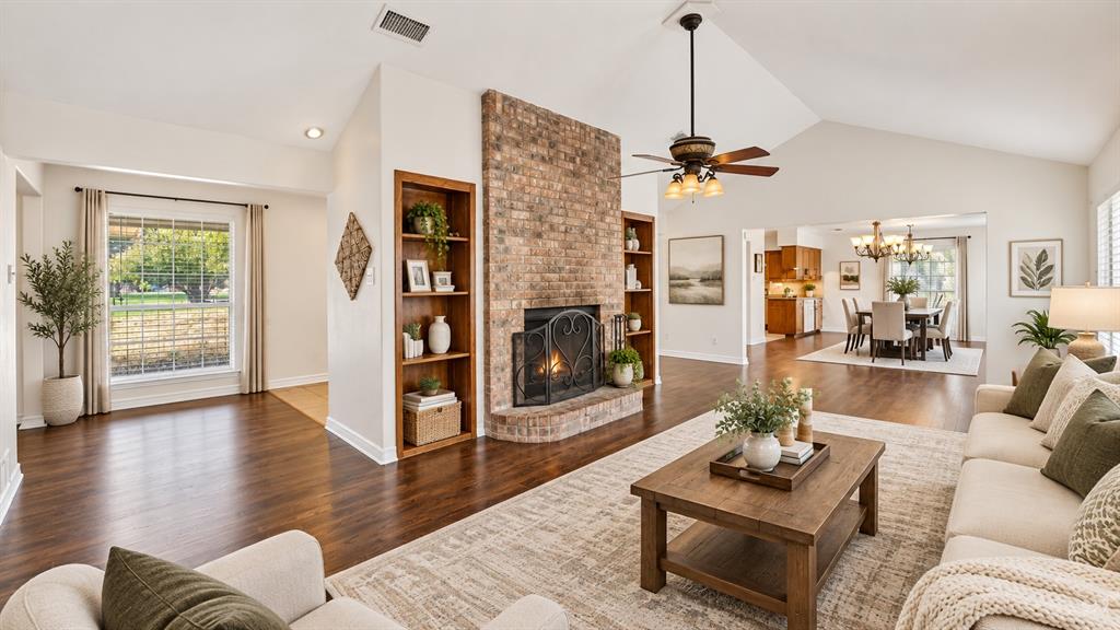 Vaulted ceilings, brick fireplace with built-in shelving, wood-finish flooring, and recessed lighting