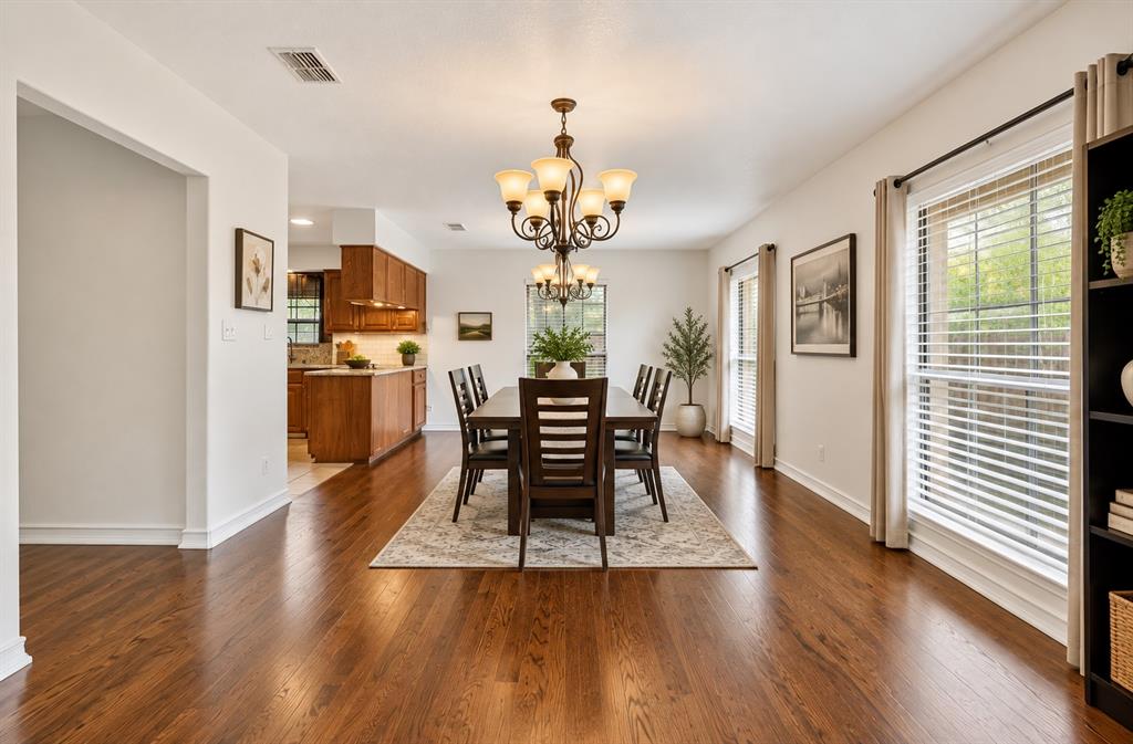 Dining area featuring wood-finish flooring, a multi-arm chandelier, and large windows with horizontal blinds