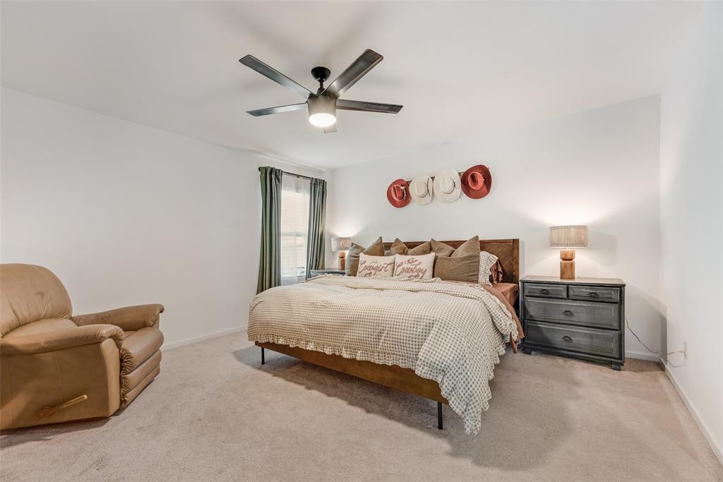 Neutral-toned carpeted flooring, window with natural lighting, and ceiling-mounted light fixture with integrated fan