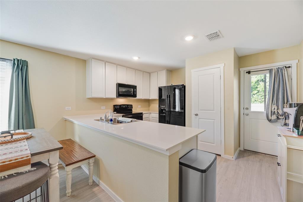 Kitchen featuring white cabinetry, solid-surface countertops, recessed lighting, wood-finish flooring, and a glass-paneled exterior door