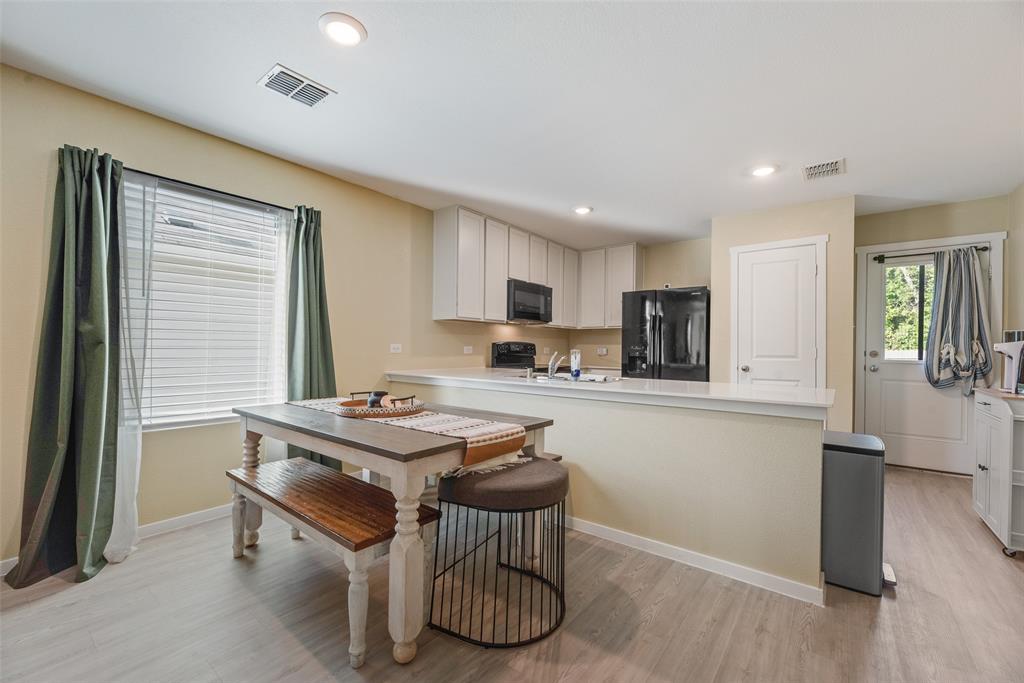 Kitchen featuring white cabinetry, a peninsula with a solid-surface countertop, recessed lighting, and wood-finish flooring