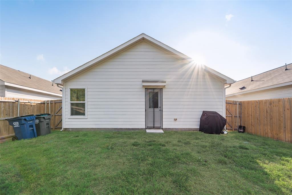 Rear exterior featuring horizontal lap siding, a single-door entrance, and a fenced backyard