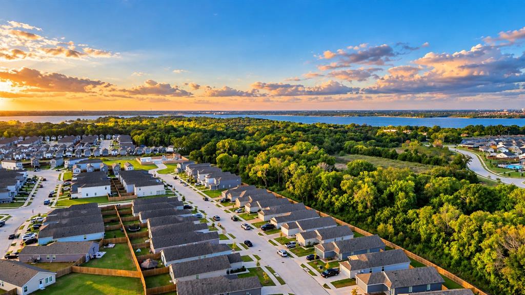 Aerial perspective featuring residential lots, dense tree coverage, and a prominent water shoreline