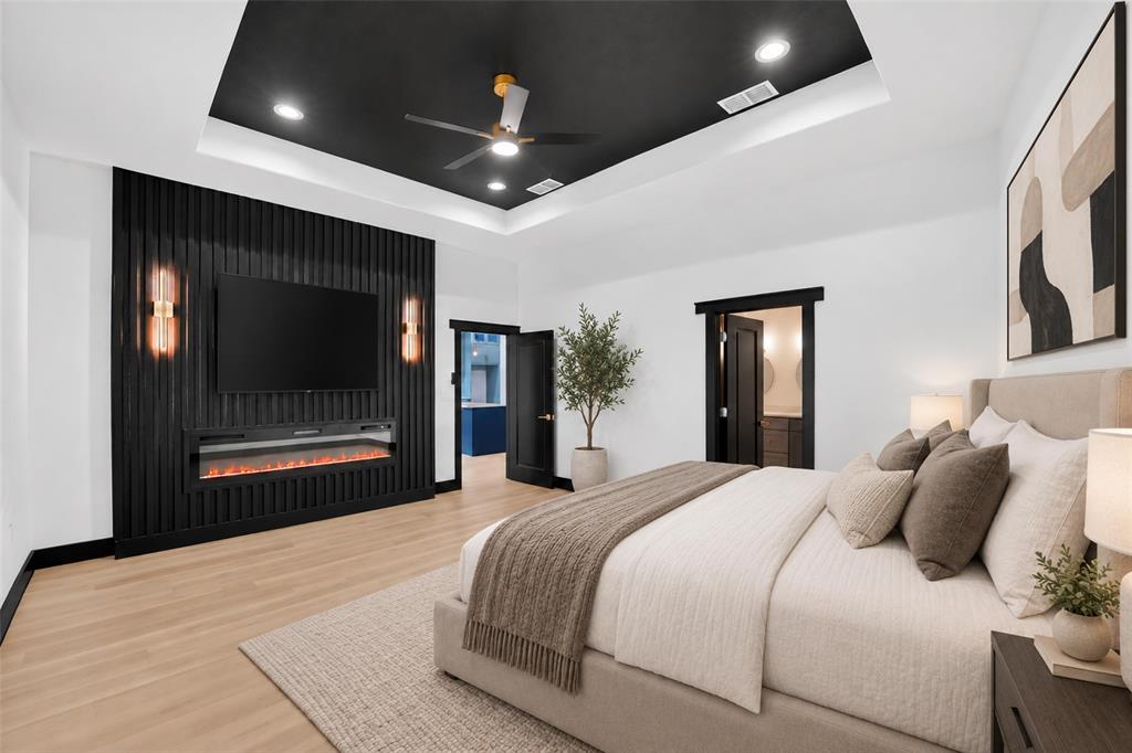 Tray ceiling with a black finish, recessed lighting, black slatted wood accent wall, built-in electric fireplace, and wood-finish flooring