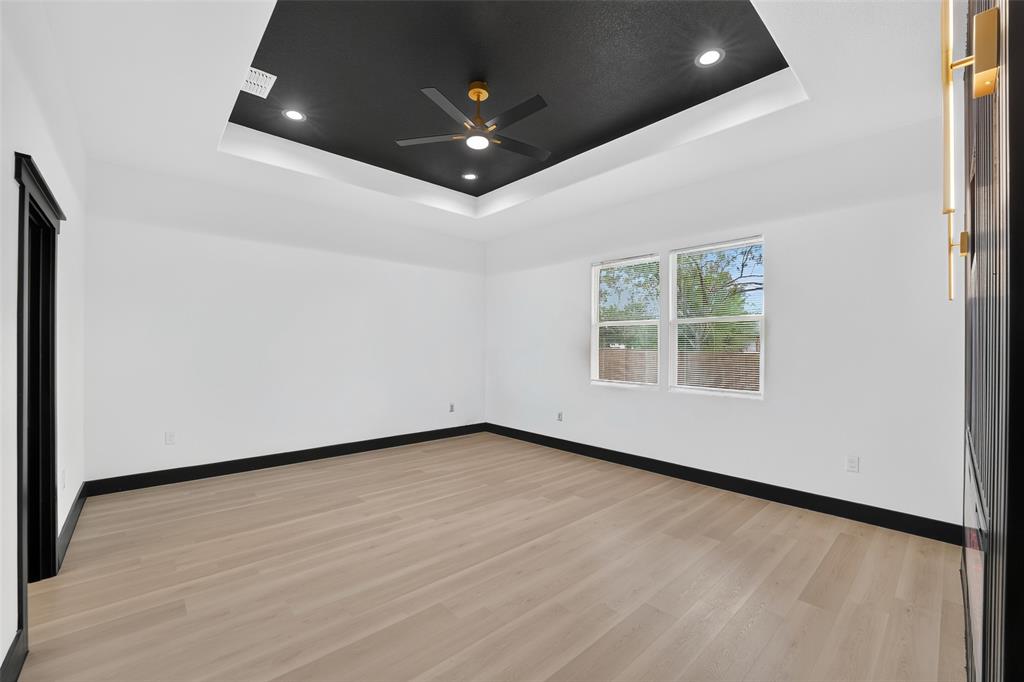 Tray ceiling featuring a contrasting black finish, light wood-finish flooring, and recessed lighting