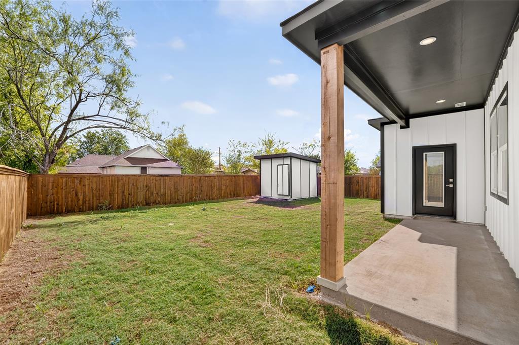 Backyard featuring a concrete patio, a covered porch with a wood-finish post, a detached storage shed, and perimeter wood fencing
