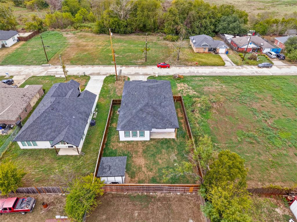 Aerial perspective of a detached single-story residence featuring a shingled roof, exterior siding, a fenced rear yard, and a detached outbuilding
