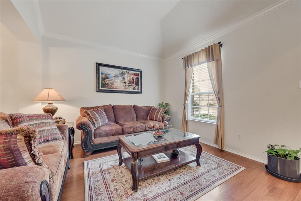 Vaulted ceiling featuring crown molding, neutral wall finishes, and wood-finish flooring