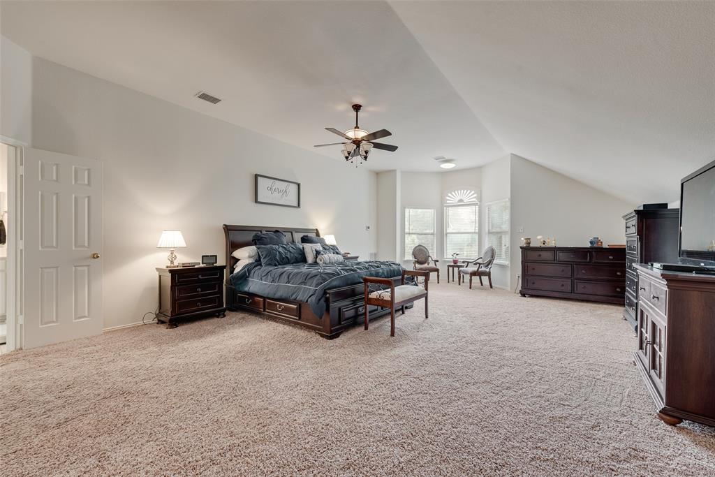 Vaulted ceilings, carpeting, a multi-windowed alcove, and an overhead ceiling fan fixture