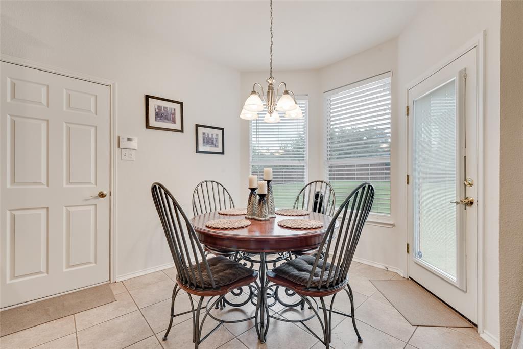 Breakfast nook featuring neutral tile flooring, a multi-light chandelier, bay windows, and a glass-paneled exterior door