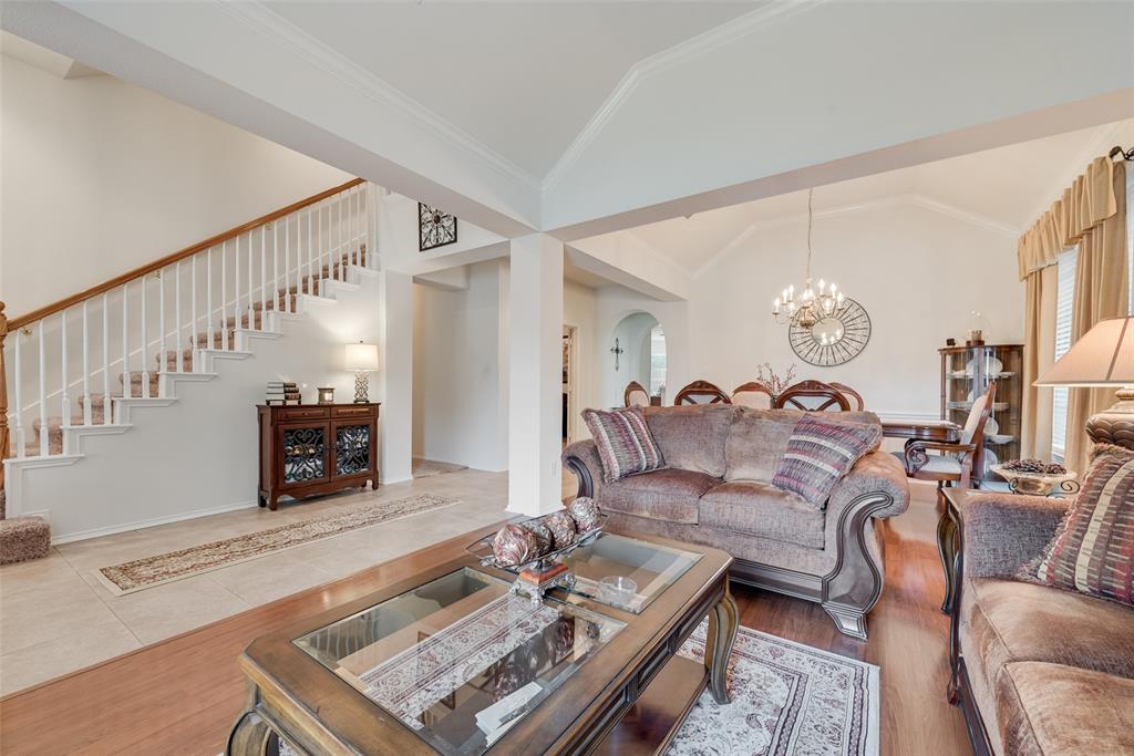 Open-concept main level featuring vaulted ceilings, a central staircase with wood handrails, large-format tile flooring, and wood-finish flooring