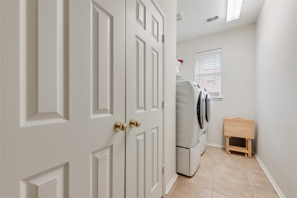 Laundry room featuring ceramic tile flooring, neutral wall paint, and a built-in closet with raised-panel doors