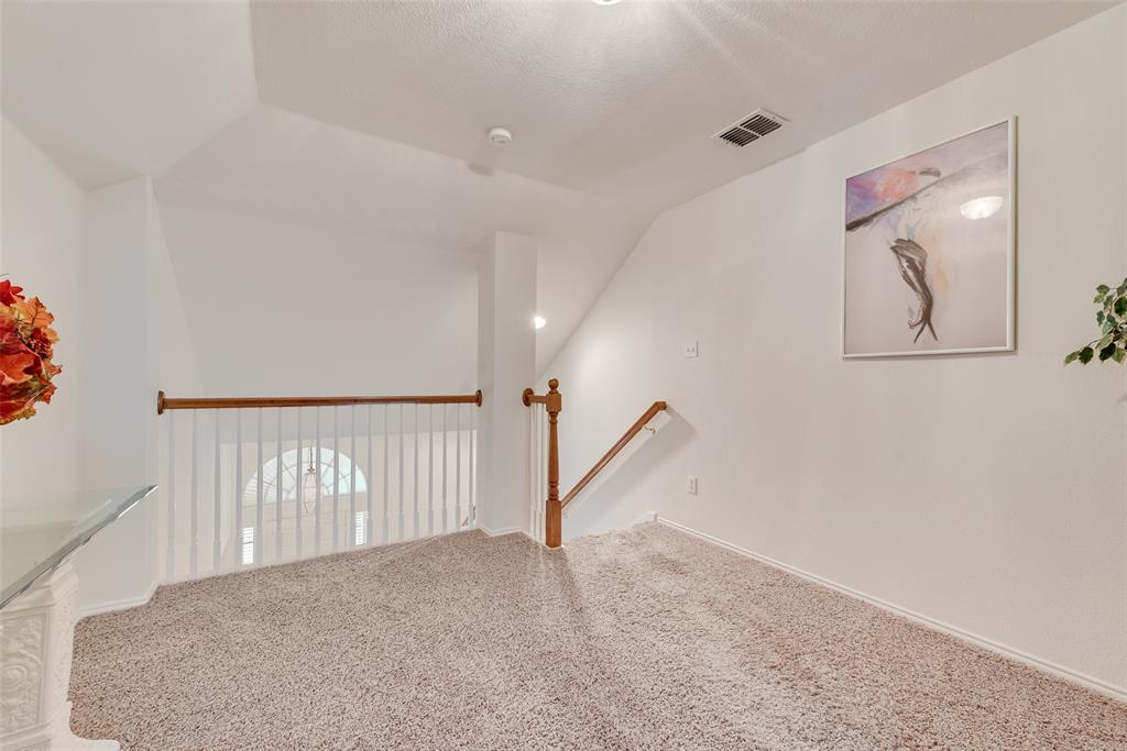 Neutral wall-to-wall carpeting, wood-finish balustrade, white spindle railing, and vaulted ceilings