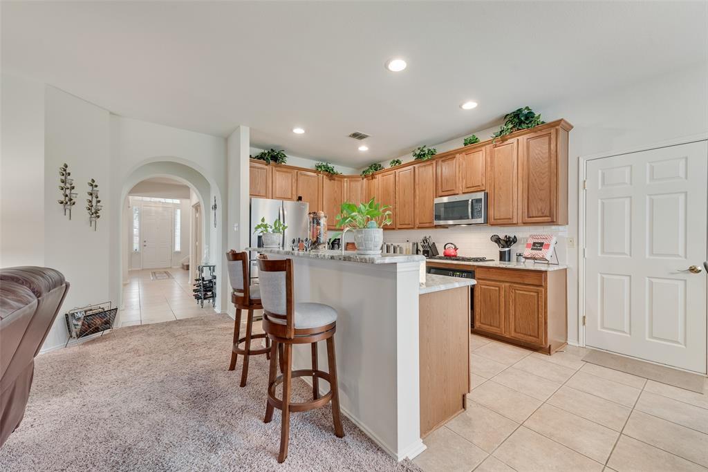 Kitchen featuring wood cabinetry, stone-finish countertops, stainless steel appliances, a breakfast bar, and recessed lighting