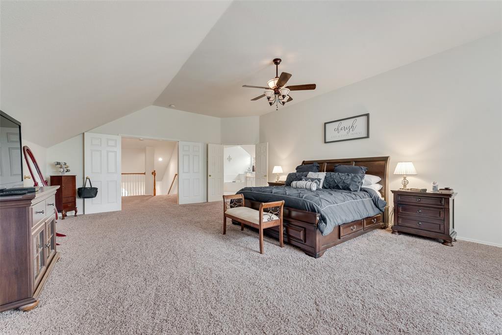 Vaulted ceiling with an integrated multi-blade ceiling fan, wall-to-wall carpeting, and double-door entry