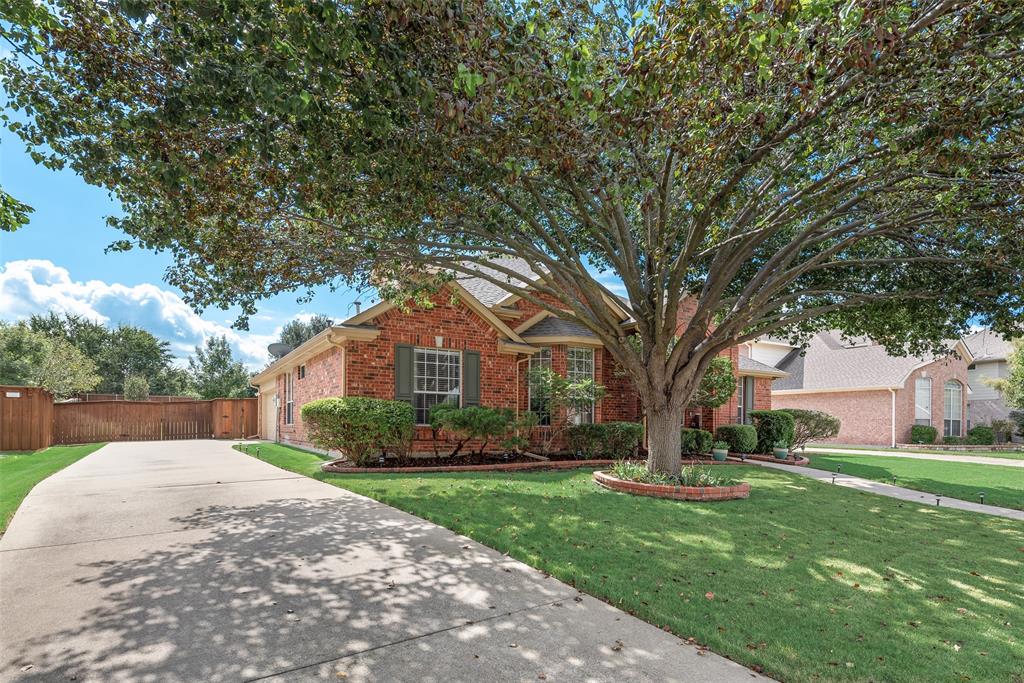 Brick exterior facade featuring a multi-gabled roofline, concrete driveway, front yard landscaping, and mature canopy tree Brick exterior facade featuring a multi-gabled roofline, concrete driveway, front yard landscaping, and mature canopy tree