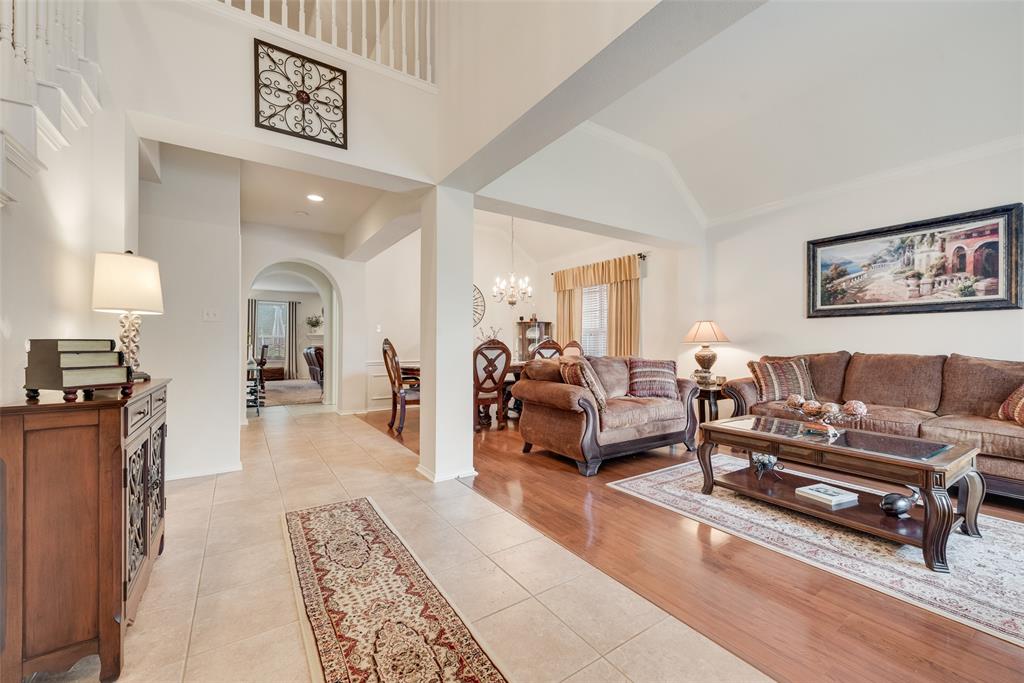 Open-concept interior featuring vaulted ceilings, neutral tile flooring, wood-finish flooring, and arched doorways