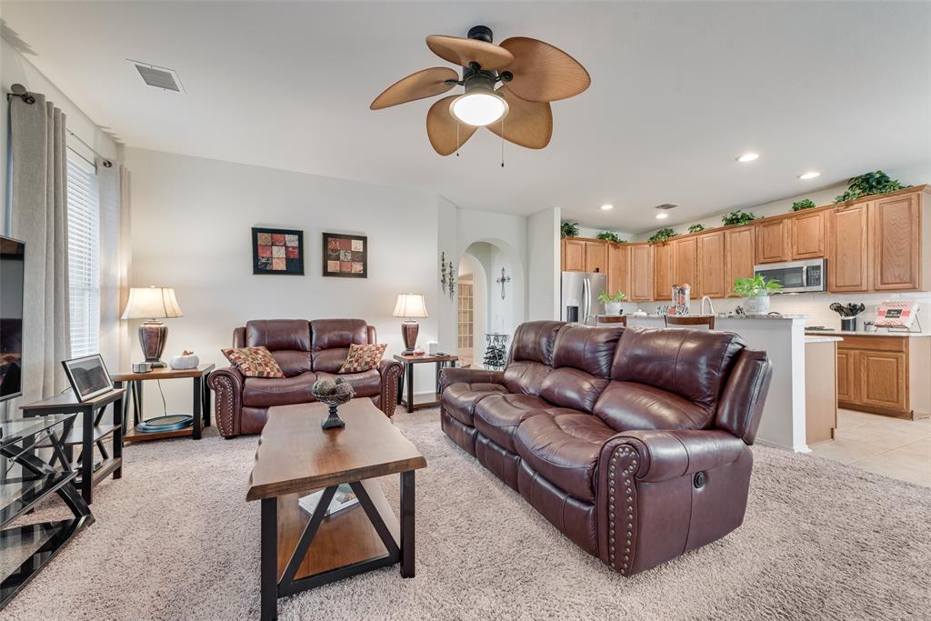 Open-concept living space featuring a palm-style ceiling fan, recessed lighting, arched entryway, and kitchen cabinetry with stainless steel appliances Open-concept living space featuring a palm-style ceiling fan, recessed lighting, arched entryway, and kitchen cabinetry with stainless steel appliances