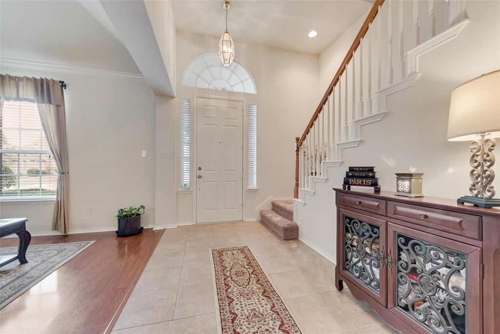 Foyer featuring tile flooring, a staircase with white balusters and wood-finish handrail, and an entryway door with arched transom window and sidelights Foyer featuring tile flooring, a staircase with white balusters and wood-finish handrail, and an entryway door with arched transom window and sidelights