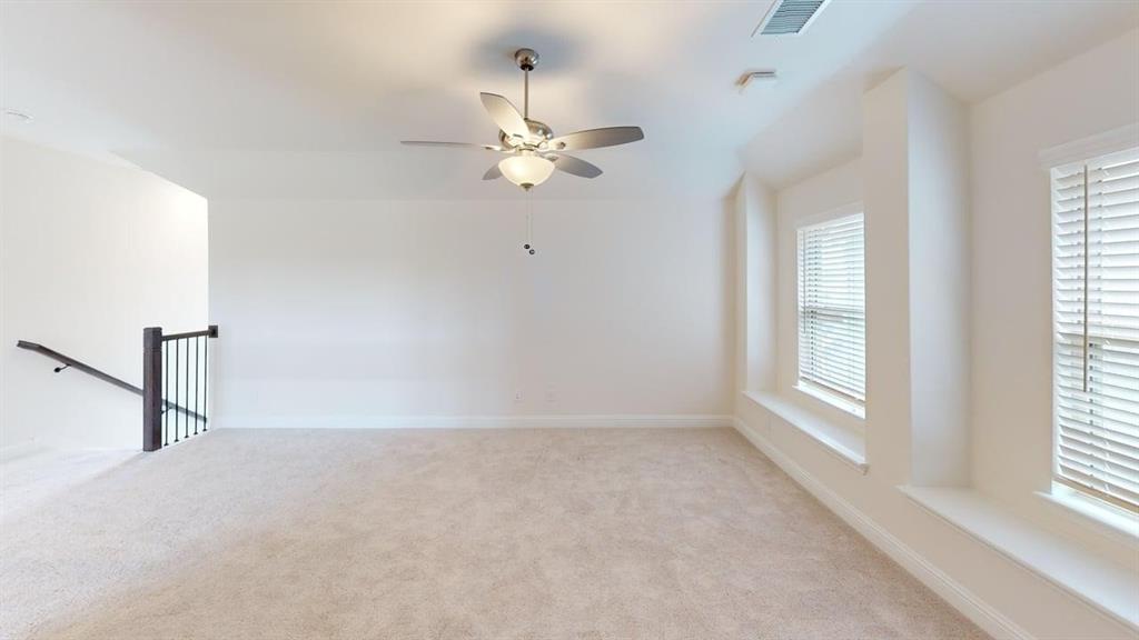 Neutral-toned interior space featuring recessed ceiling lighting, a central brushed-nickel ceiling fan with integrated light fixture, carpeted flooring, and built-in window seating with horizontal blinds