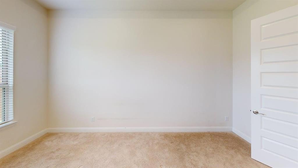 Interior space featuring neutral-toned carpeting, five-panel interior door with brushed nickel hardware, and window with horizontal blinds