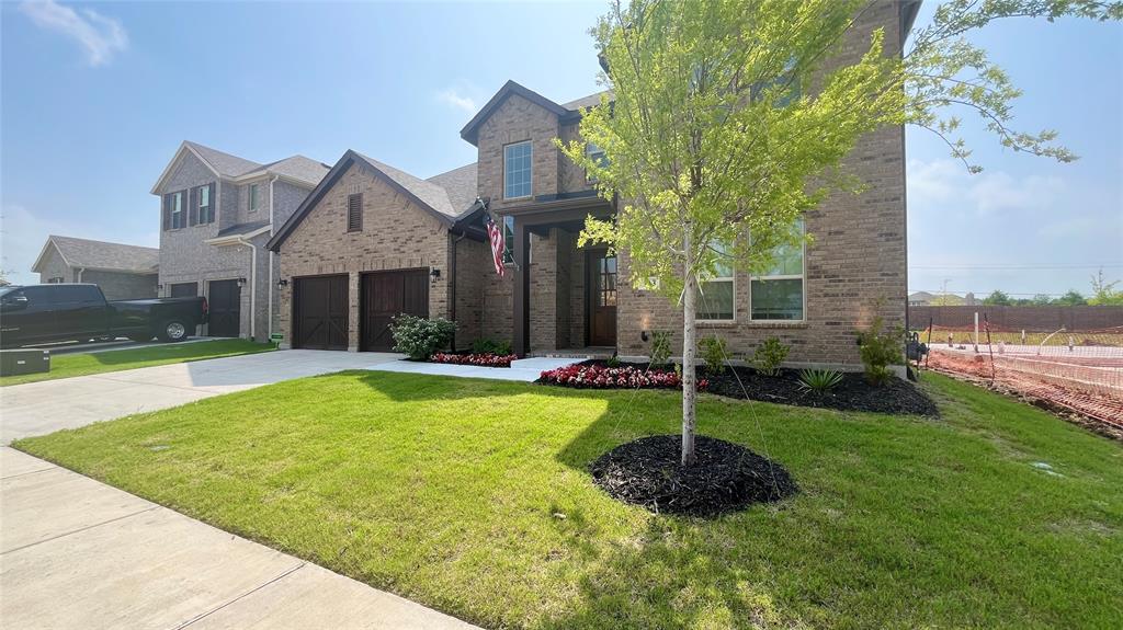 Multi-story brick exterior featuring a covered entryway, dual garage bays with wood-finish doors, and landscaped front garden beds