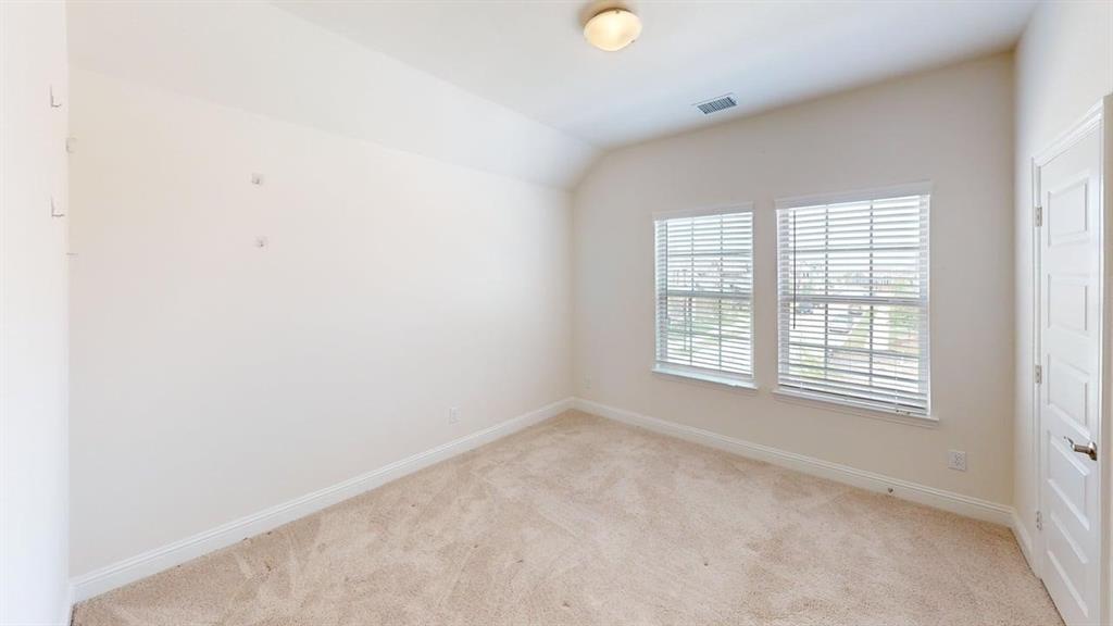 Interior room featuring neutral wall tones, plush wall-to-wall carpeting, vaulted ceilings, dual pane windows with horizontal blinds, and a paneled interior door