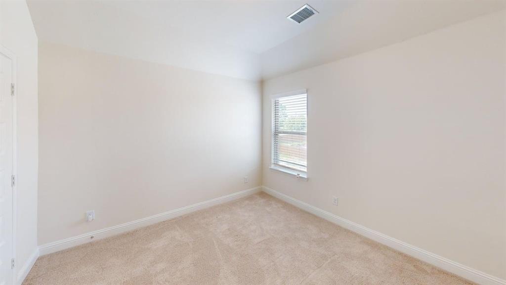 Neutral-toned interior space featuring neutral wall-to-wall carpeting, high tray ceilings, and a window with horizontal blinds