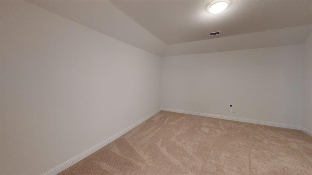 Interior room featuring neutral-toned carpeting, high tray ceilings, and an overhead flush-mount light fixture