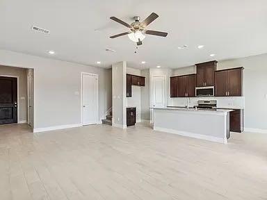 Open-concept kitchen featuring dark wood cabinetry, a breakfast bar, recessed lighting, and light-toned flooring throughout