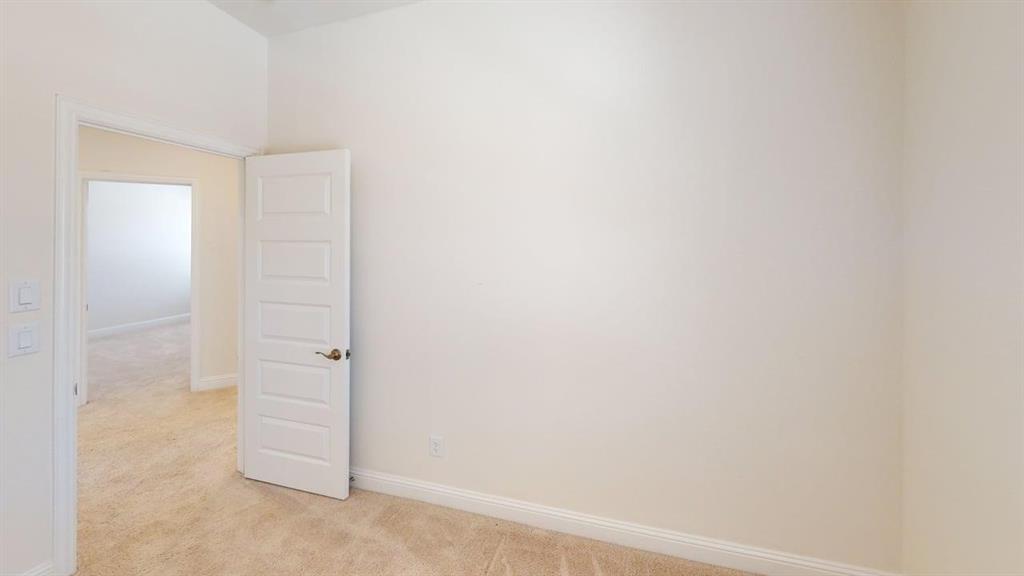 Neutral wall tones, carpeting, and five-panel interior door with brushed metal hardware