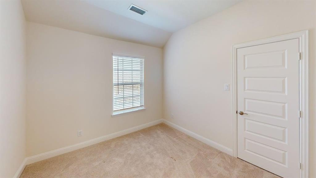 Neutral interior space featuring vaulted ceilings, neutral-toned wall-to-wall carpeting, a multi-panel interior door, and a single-hung window with blinds