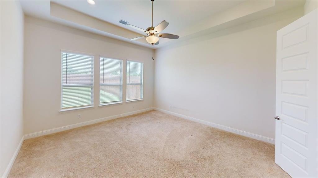 Room featuring a tray ceiling, ceiling fan with light kit, neutral carpeting, and triple-window configuration with horizontal blinds