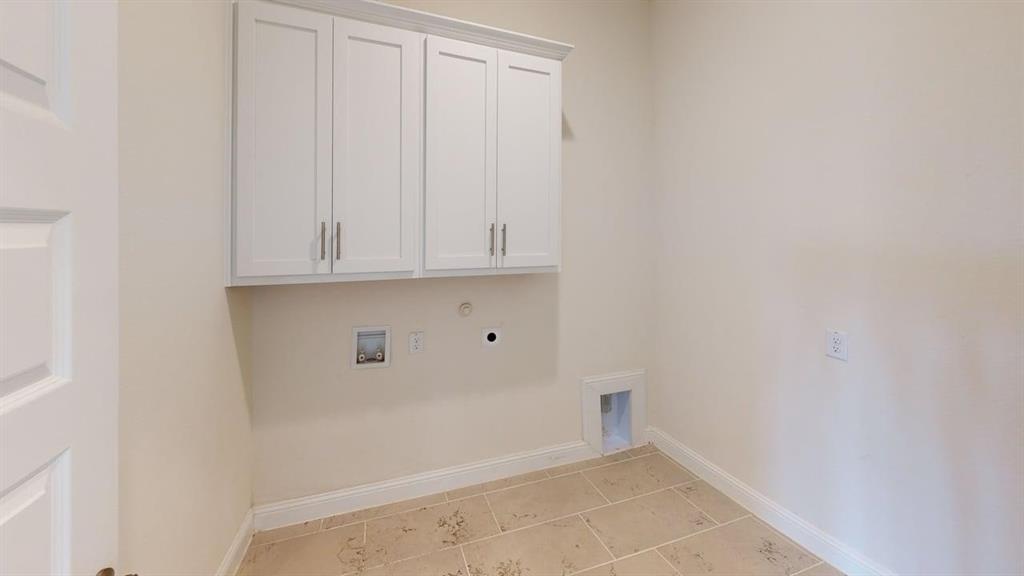 Utility space featuring white shaker-style wall cabinetry with brushed nickel hardware and neutral tile flooring