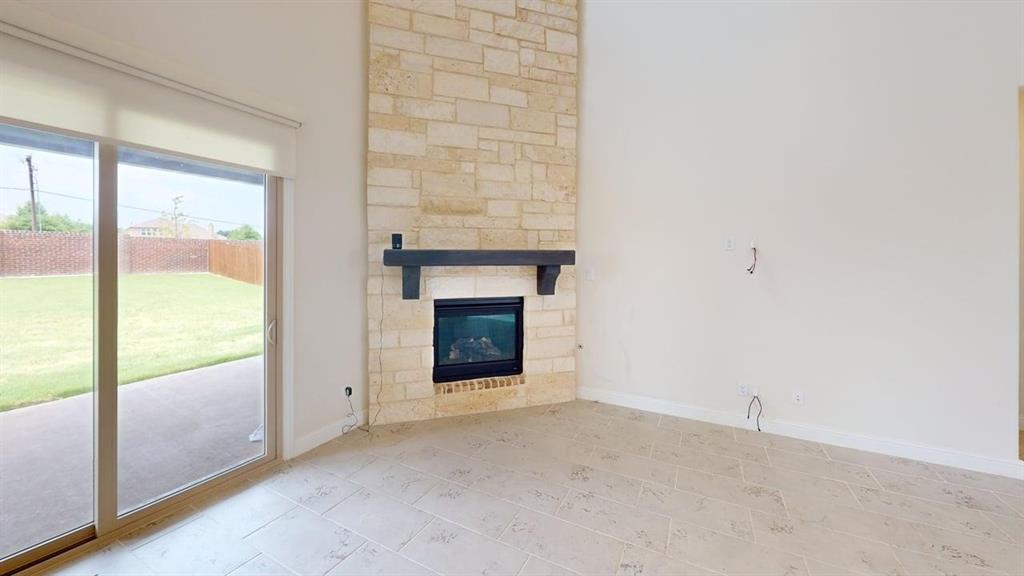 Floor-to-ceiling stone fireplace with a dark wood mantel, sliding glass door, and tile flooring
